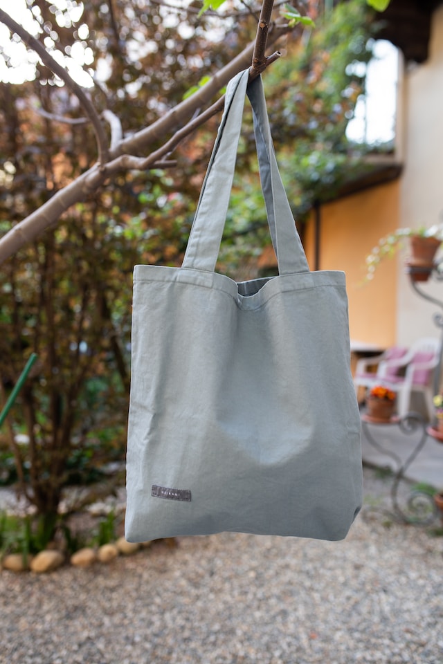 Grey bag, holding by a tree. 